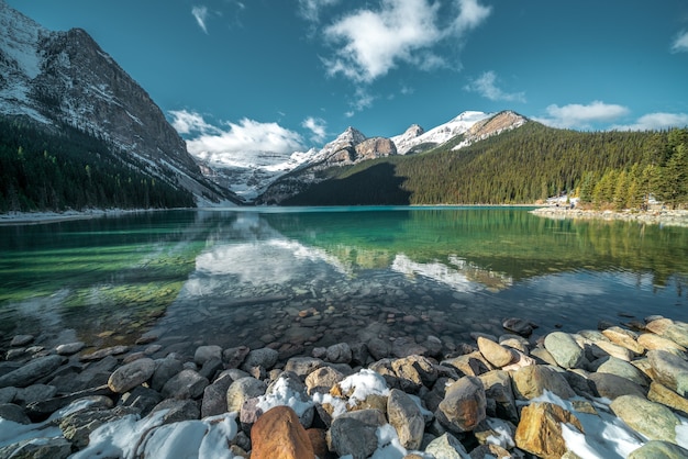 Бесплатное фото Захватывающий снимок красивых камней под бирюзовой водой озера и холмов на заднем плане