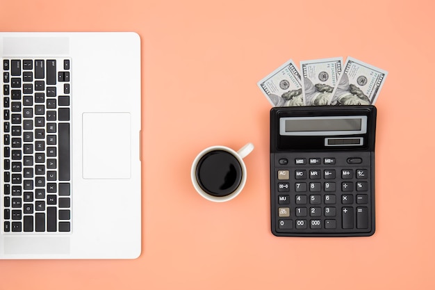 Foto gratuita calcolatrice portatile tazza di caffè e banconote da un dollaro su sfondo colorato piatto