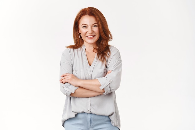 Free photo caring lovely happy middle-aged redhead woman cross arms chest smiling joyfully talking lively discuss child grades school teacher grinning laughing have interesting conversation, white wall