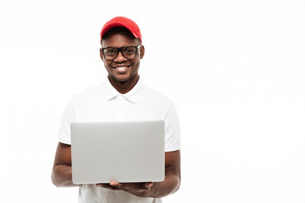 Крышка жизнерадостного молодого человека нося используя портативный компьютер