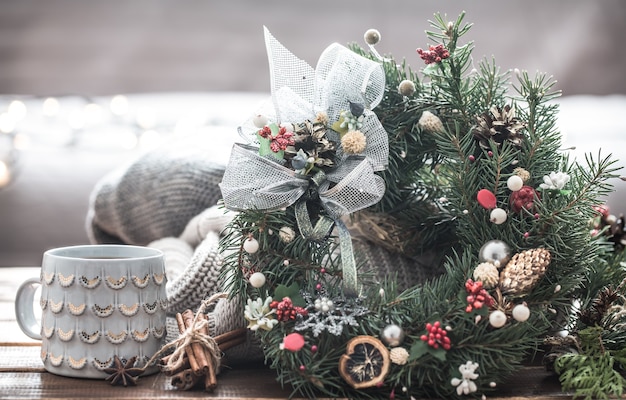 Бесплатное фото Рождественский натюрморт из елок и украшений, праздничный венок на фоне вязанной одежды и красивых чашек, рождественские специи