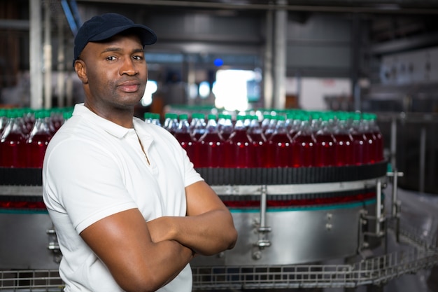 Free photo confident male employee with arms crossed standing in factory