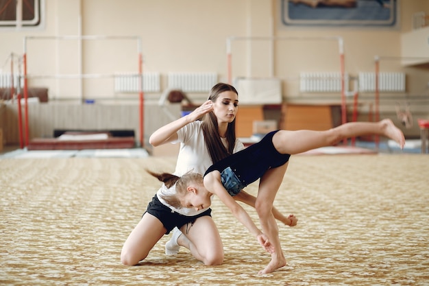 Coach with student. Girls gymnasts, performs various gymnastic exercises and jumping. Childs and sport, a healthy lifestyle.