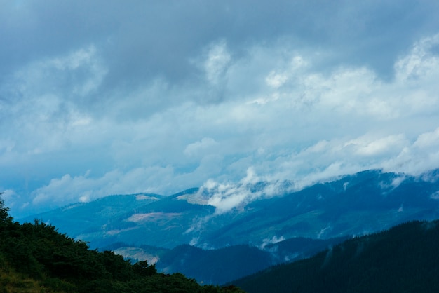 Бесплатное фото Облака над горой покрыты зелеными деревьями
