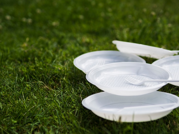 Free photo close-up of white plastic plate and fork on grass at park