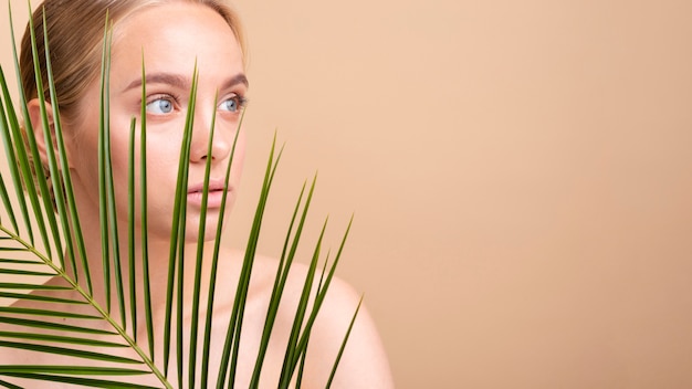 Close-up blonde model behind a plant