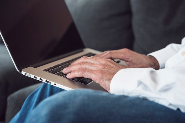 Free photo close-up of an elderly man's hand typing on laptop