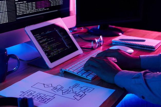Бесплатное фото Крупным планом изображение программиста, работающего на своем столе в офисе