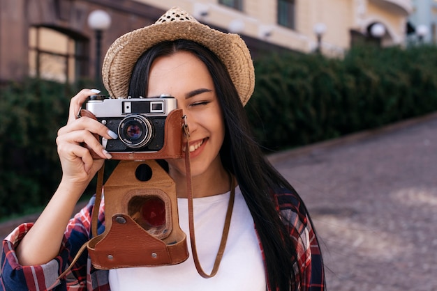 Бесплатное фото Конец-вверх счастливой молодой женщины принимая фото с камерой на outdoors