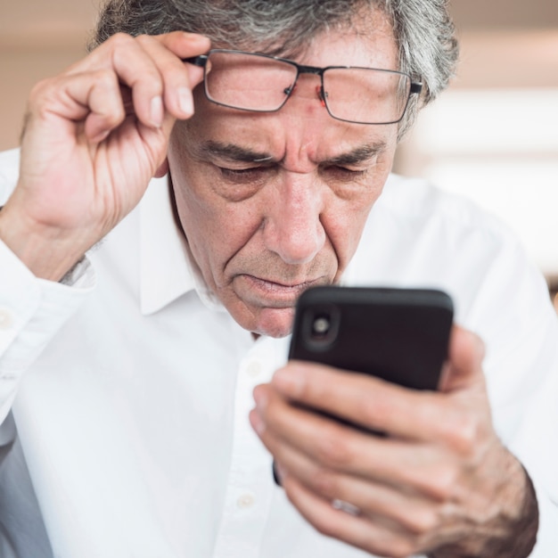 Free photo close-up of serious senior man looking at smart phone