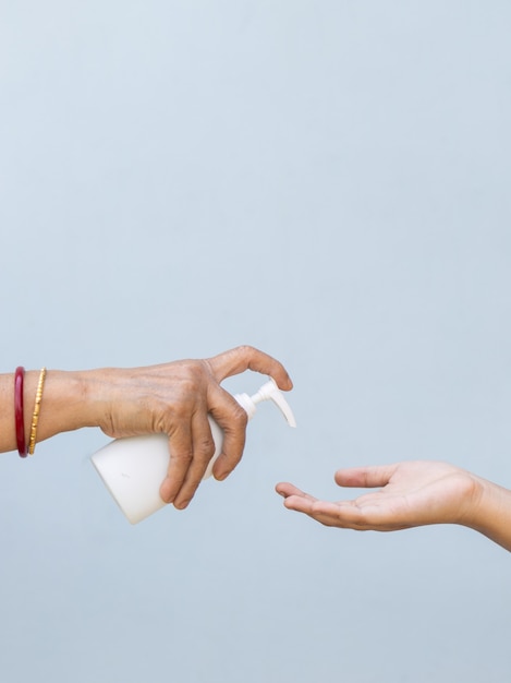Снимок крупным планом человека, наливающего жидкое мыло в руку другому человеку