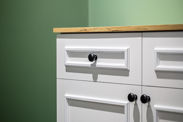 Free photo closeup of a white cabinet with black handles on a green wall background