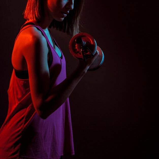 Обрезать атлетическую тренировку женщины бицепсом в темноте
