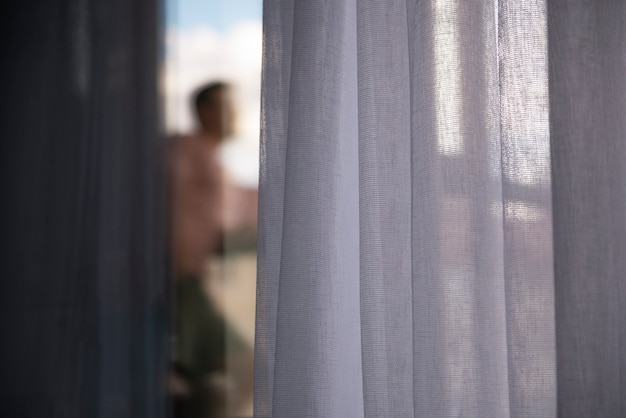 Free photo creative portrait of man with curtains and shadows from window