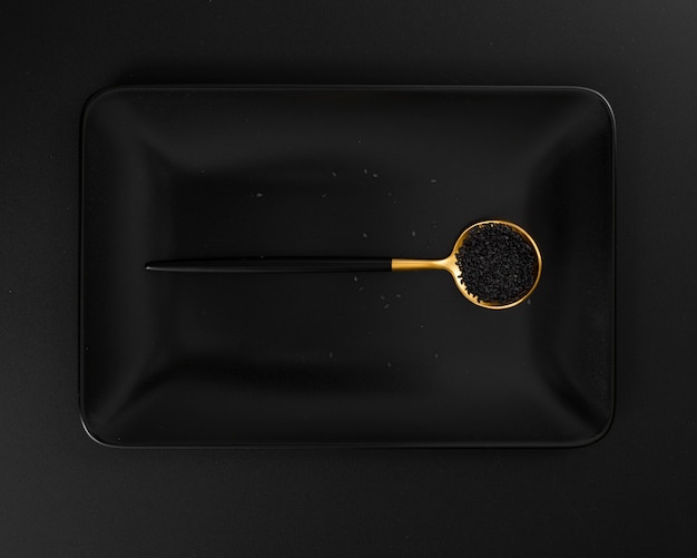 Темная тарелка с ложкой мака на темном фоне