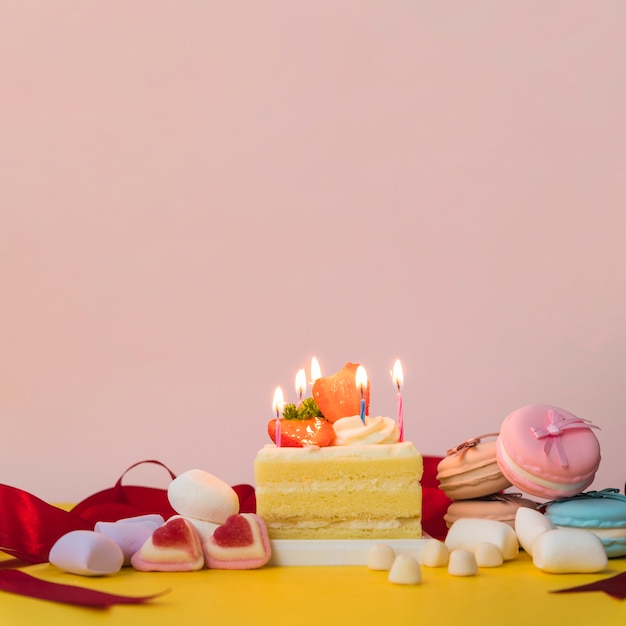 Бесплатное фото Украшенные торты конфетами; зефир и макароны на желтом столе