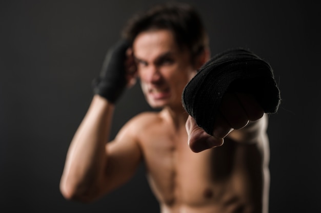 Бесплатное фото Расфокусированным мускулистый мужчина без рубашки с боксерскими перчатками