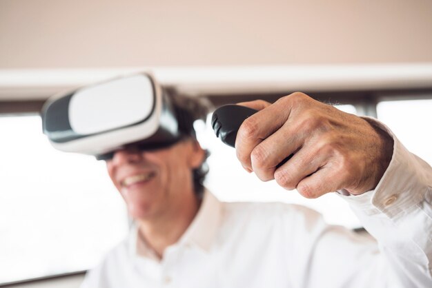 An elderly man wearing virtual reality goggles using remote control