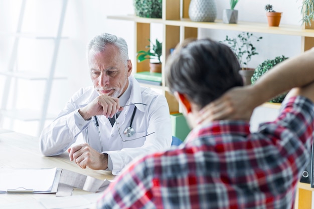 Free photo elderly doctor thinking while talking with patient
