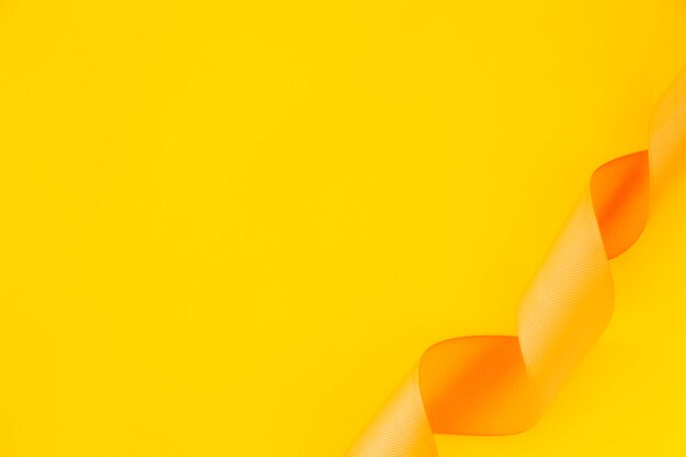 Повышенный вид скрученной атласной ленты на желтом фоне