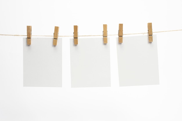 Free photo empty paper frames that hang on a rope with clothespins and isolated on white. blank cards on rope.
