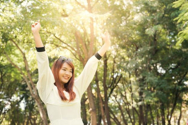 Enjoying the nature. Young asian woman arms raised enjoying the fresh air in green forest.