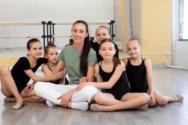 Female ballet trainer posing with girls at the gym