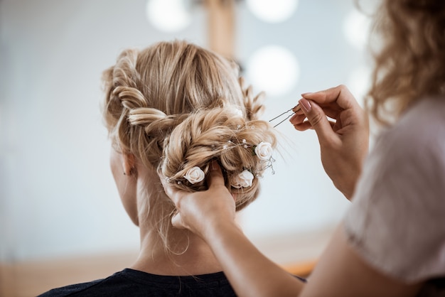 Free photo female hairdresser making hairstyle to blonde woman in beauty salon