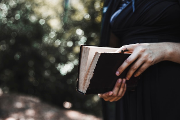 Бесплатное фото Женщина в черном холдинг книга в лесу