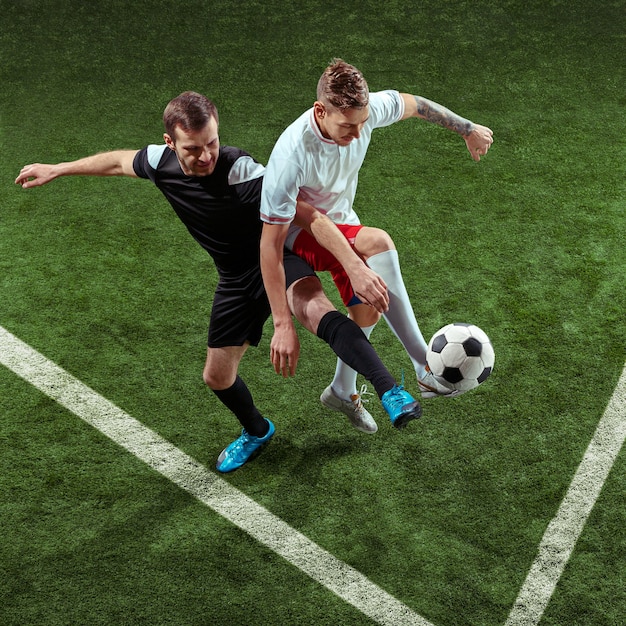 Футболист решает мяч на фоне зеленой травы.