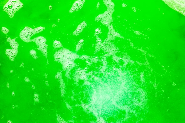 Foam and bubbles on green colored liquid
