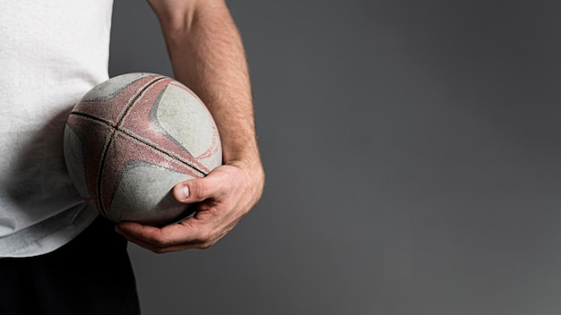 Front view of male rugby player holding ball next to hip with copy space