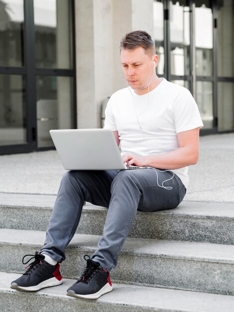 Вид спереди человека на открытом воздухе на шагах, работающих на ноутбуке