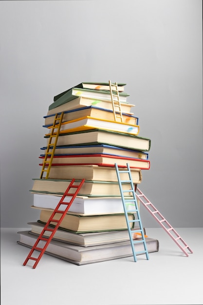 Бесплатное фото Вид спереди сложенных книг и лестниц с местом для копирования на день образования