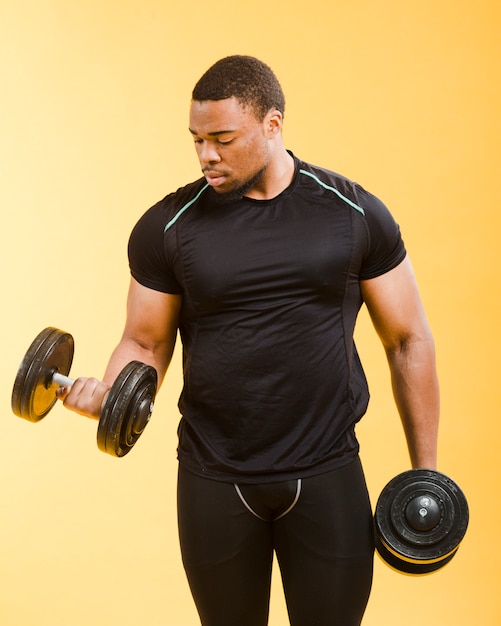 Вид спереди спортивного человека, держащего весы в спортивном наряде