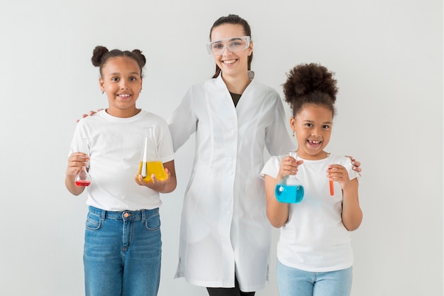 Free photo front view of female scientist posing with young girls holding test tubes