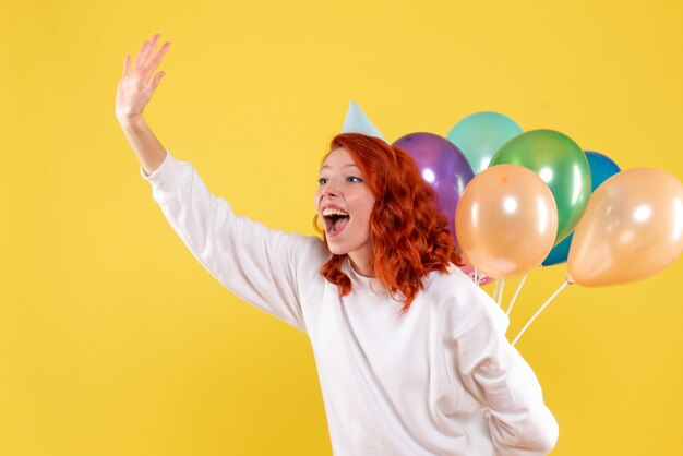 Вид спереди молодая женщина, пряча разноцветные шары за спиной цвета нового года