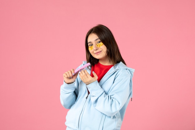 Free photo front view of young woman with eye patches and nail file on pink wall