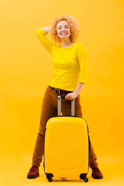 スーツケースを持つ金髪の女性の完全なショット
