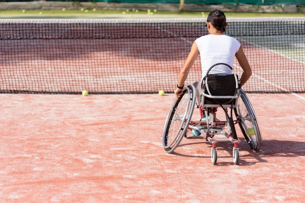 Женщина-инвалид в полный рост играет в теннис