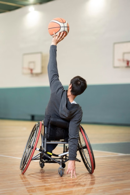 Полный снимок человека в инвалидной коляске на баскетбольной площадке