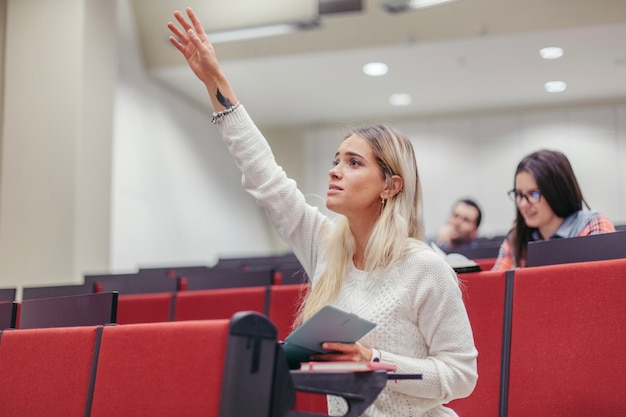 Бесплатное фото Девушка поднимает руку в лекционный зал