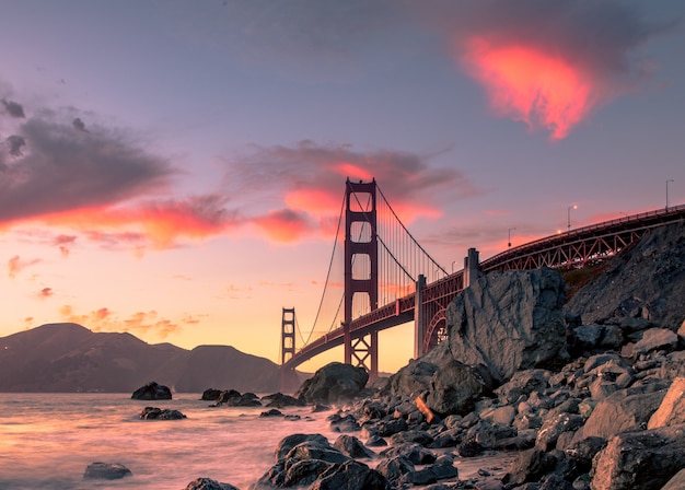 Golden Gate Bridge on body of water near rock formations during sunset in San Francisco, California