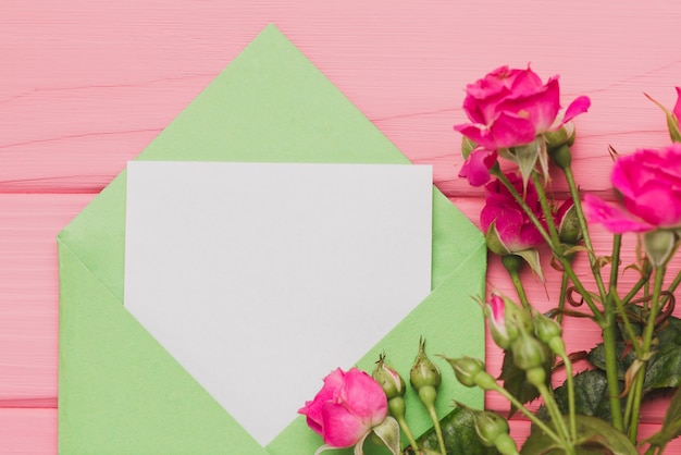 Бесплатное фото Зеленый конверт с пустым запиской и розы