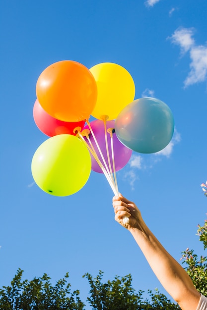 Бесплатное фото Рука держит коллекцию ярких воздушных шаров
