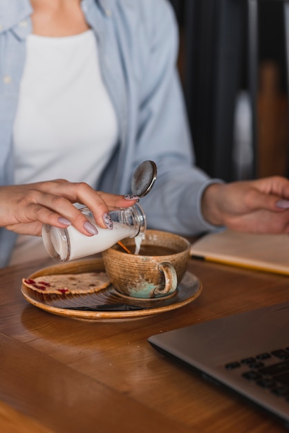 Бесплатное фото Рука наливает молоко в чашку кофе