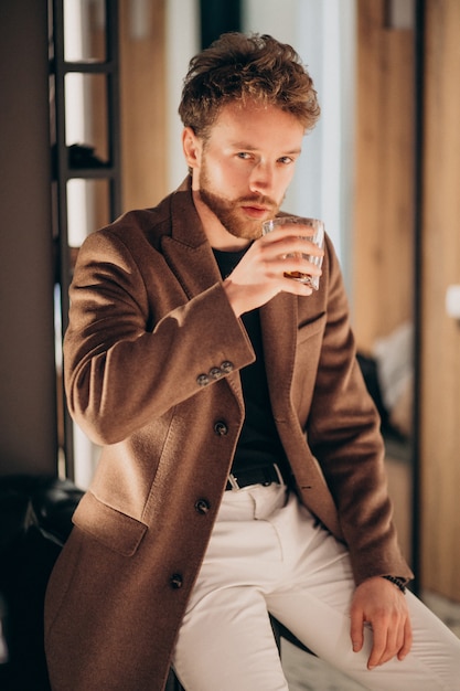Бесплатное фото Красивый бородатый мужчина пьет виски