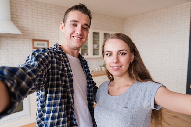 Foto gratuita giovani coppie felici insieme facendo selfie in cucina