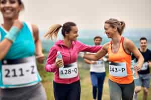 Бесплатное фото Счастливые спортсменки поддерживают друг друга во время марафона на природе