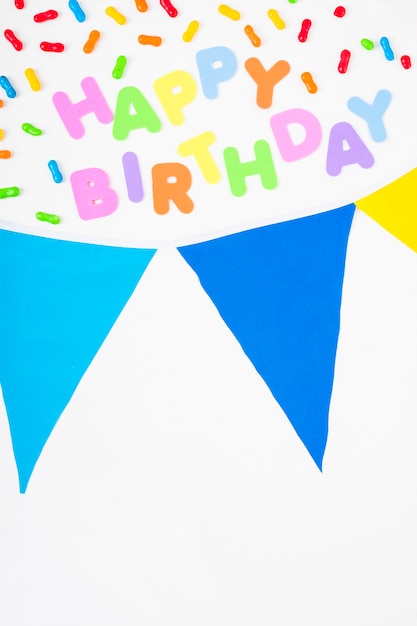 Free photo happy birthday text with candies and bunting on white background